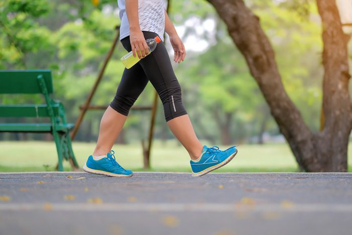 cropped shot - lower portion of a person walking for exercise and holding a drink - exercise and mental health