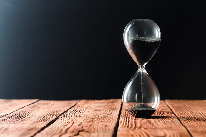 hourglass with black sand on wooden table - drugs or alcohol