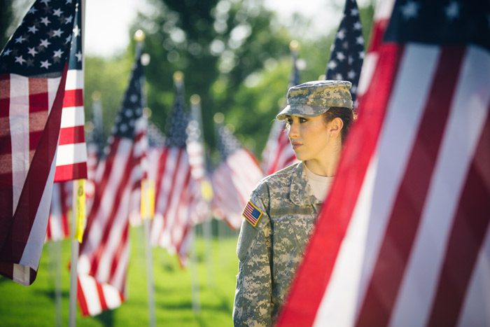 female soldier at cemetery filled with large American flags - mental health for vets