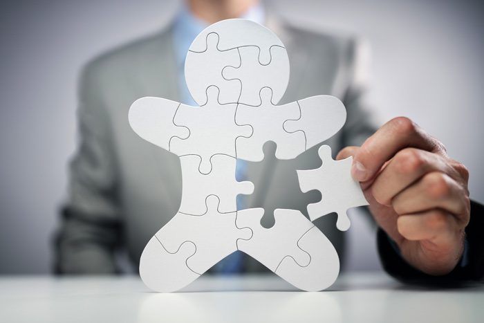 man putting last piece of puzzle in person shaped puzzle - whole person